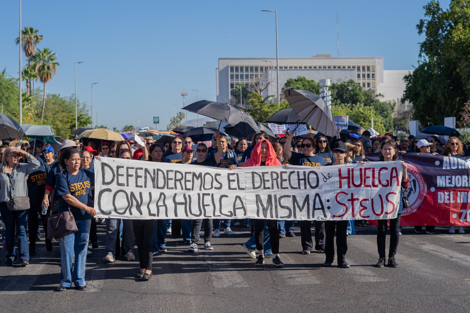 Contingente sosteniendo la lona principal con las 8 demandas laborales durante el desfile del Día del Trabajo en Hermosillo.